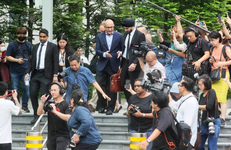 Singapurs ehemaliger Verkehrsminister S. Iswaran verlässt das Gericht.  Er ist von Journalisten umgeben. 