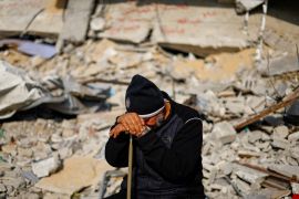 A Palestinian man leans his head against his cane amid the rubble of a destroyed building in Gaza