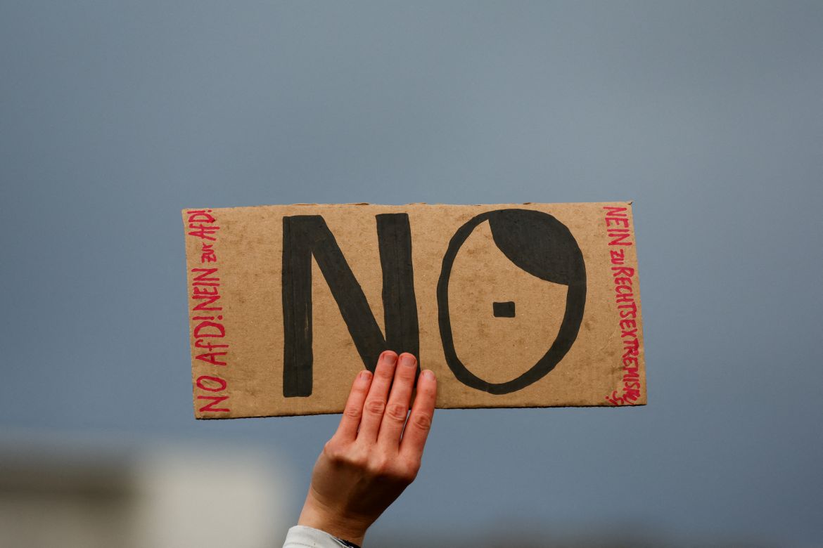 A person holds a placard as people gather outside the Reichstag building, during a rally of the broad alliance "Hand in Hand" under the slogan "Wir sind die Brandmauer" ("We are the Firewall") to protest against right-wing extremism and for the protection of democracy, in Berlin, Germany February 3