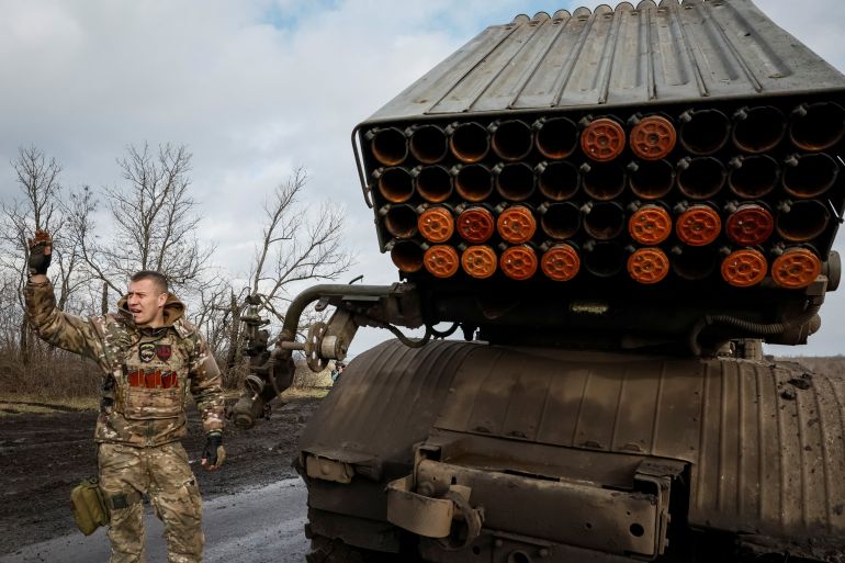 A Ukrainian soldier next to a BM-21 Grad multiple launch rocket system. He is signalling to a colleague.