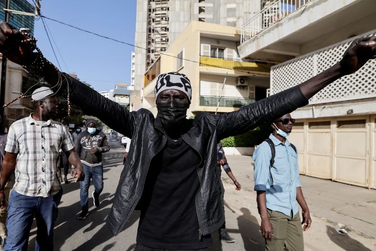 A protester in Dakar, He is holding his arms out as he walks through the street