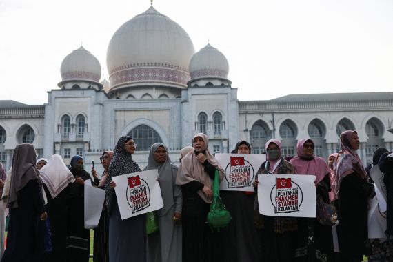 Muslim women protest outside the Federal Court ahead of Friday's verdict. They are holding placards reading 'Pertahan Enakmen Syariah Kelantan' (Defend Kelantan sharia law)