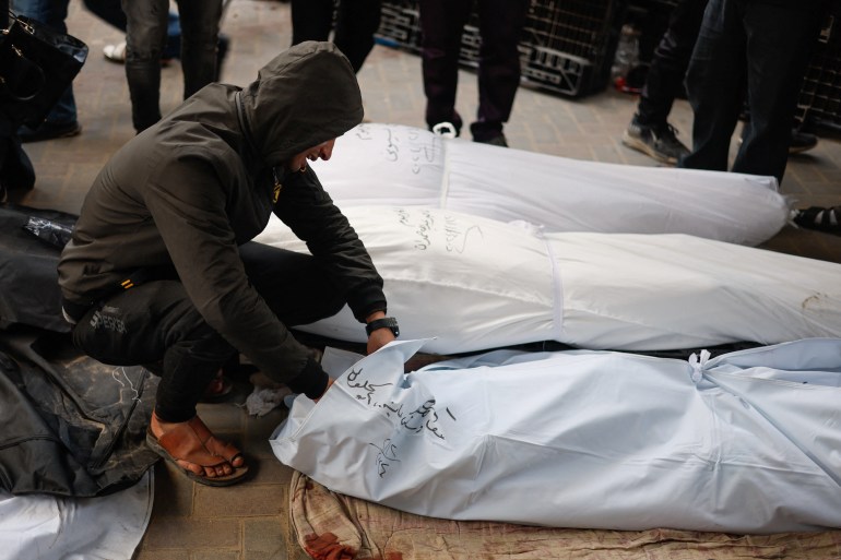 A man reacts next to the bodies of Palestinians killed in Israeli strikes