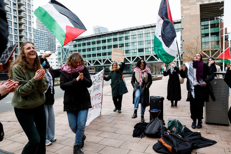Demonstrators hold flags during a protest outside the court building,