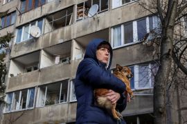 A local resident holds her dog as she stands near her apartment building damaged during a Russian missile strike, amid Russia’s attack on Ukraine, in Lviv, Ukraine February 15, 2024. REUTERS/Roman Baluk     TPX IMAGES OF THE DAY