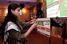 Activist Natalia Latif tapes a Vote Uncommitted sign on the speaker&#039;s podium during an uncommitted vote election night gathering as Democrats and Republicans hold their Michigan primary presidential election, in Dearborn, Michigan, US, February 27, 2024 [Rebecca Cook/Reuters]