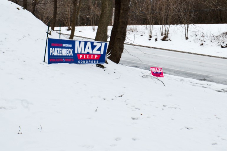Des panneaux de campagne pour le district 3 de New York sont posés dans un banc de neige.