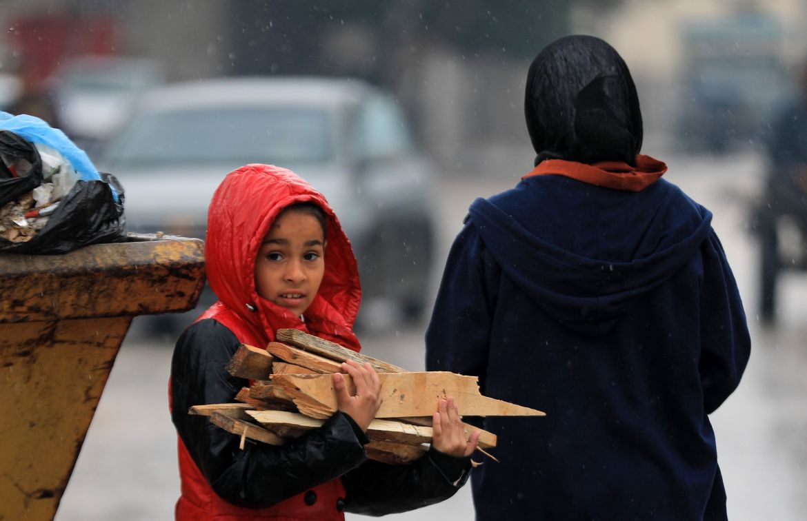 A Palestinian child is seen carrying firewood as Palestinians who fled the Israeli army attacks and took refuge in Rafah try to survive under difficult conditions with makeshift tents in Rafah, Gaza on February 18