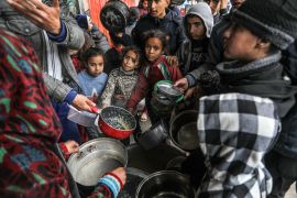 Palestinians holding empty bowls receive food distributed by volunteers in Rafah, Gaza on February 18, 2024 [Abed Rahim Khatib/Anadolu Agency]