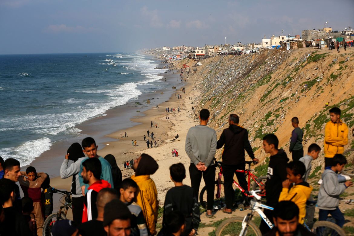 Palestinians wait for humanitarian aid airdrop at the beach in Deir al Balah,