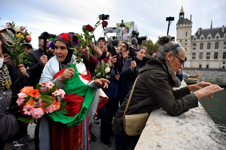 Women throw roses into the Seine river