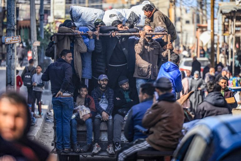 Gazze Şeridi'ndeki çatışmalardan kaçanlar bir kamyonun arkasında Refah'ta aşırı kalabalık bir caddede ilerliyor