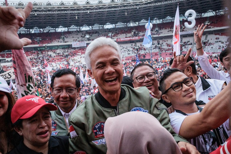 Ganjar Pranowo among supporters. He is shaking hands and smiling. He is at an event in a stadium.