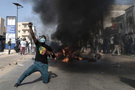 An opposition supporter reacts in front of a burning barricade during demonstrations called by the opposition parties in Dakar on February 4, 2024