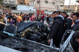 People gather to inspect the remains of a wrecked police vehicle that was destroyed by reported Israeli bombardment in Rafah