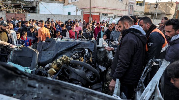 People gather to inspect the remains of a wrecked police vehicle that was destroyed by reported Israeli bombardment in Rafah