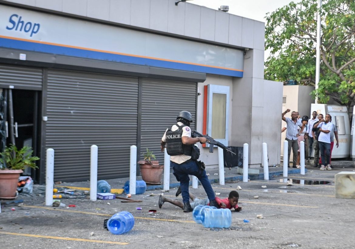 Haitian policeman kicks a child