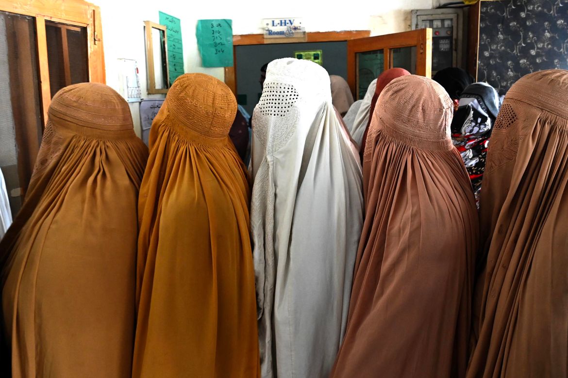 Burqa-clad women line up to cast their ballots to vote at a polling station during Pakistan's national elections in Peshawar