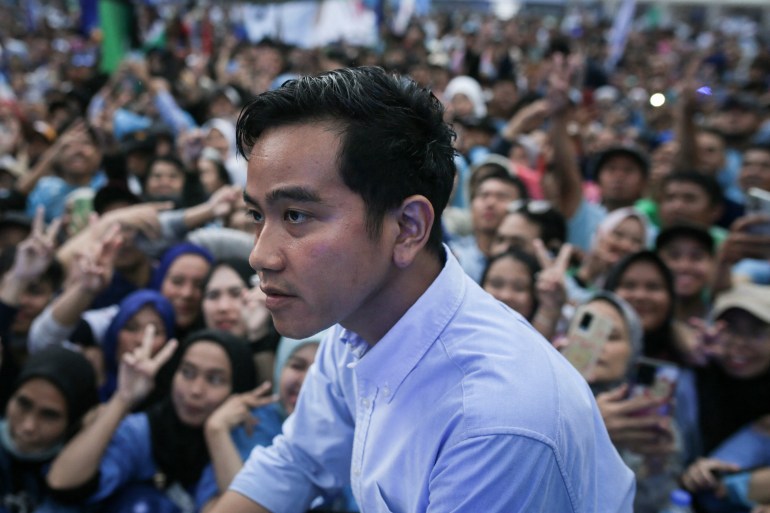Vice presidential candidate Gibran Rakabuming Raka. He looks pensive. There are large crowds behind him.