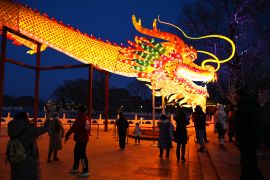 People gather to look at a giant dragon figure at a park in Beijing on February 9, 2024, which marks the eve of the Lunar New Year of the Dragon [Greg Baker/AFP]