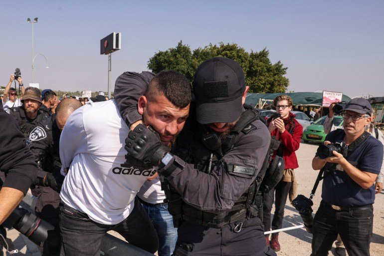 Membros das forças de segurança israelenses prendem um manifestante enquanto ativistas israelenses e palestinos protestavam contra a guerra em curso de Israel em Gaza, em um cruzamento que leva à cidade de Jericó, na Cisjordânia ocupada, em 9 de fevereiro de 2024. (Foto de HAZEM BADER / AFP)