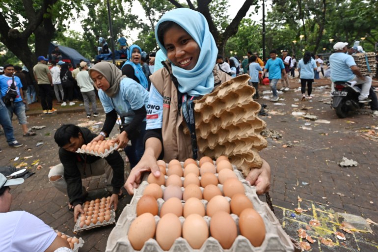 Una mujer muestra una bandeja de huevos que le regalaron después de un mitin de campaña en Indonesia.