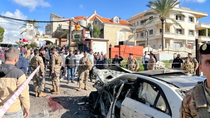 Blood stains cover the ground next to a a car wrecked in a reported Israeli drone attack, as Lebanese army soldiers secure the area in the village of Jadra between Beirut and the southern city of Sidon