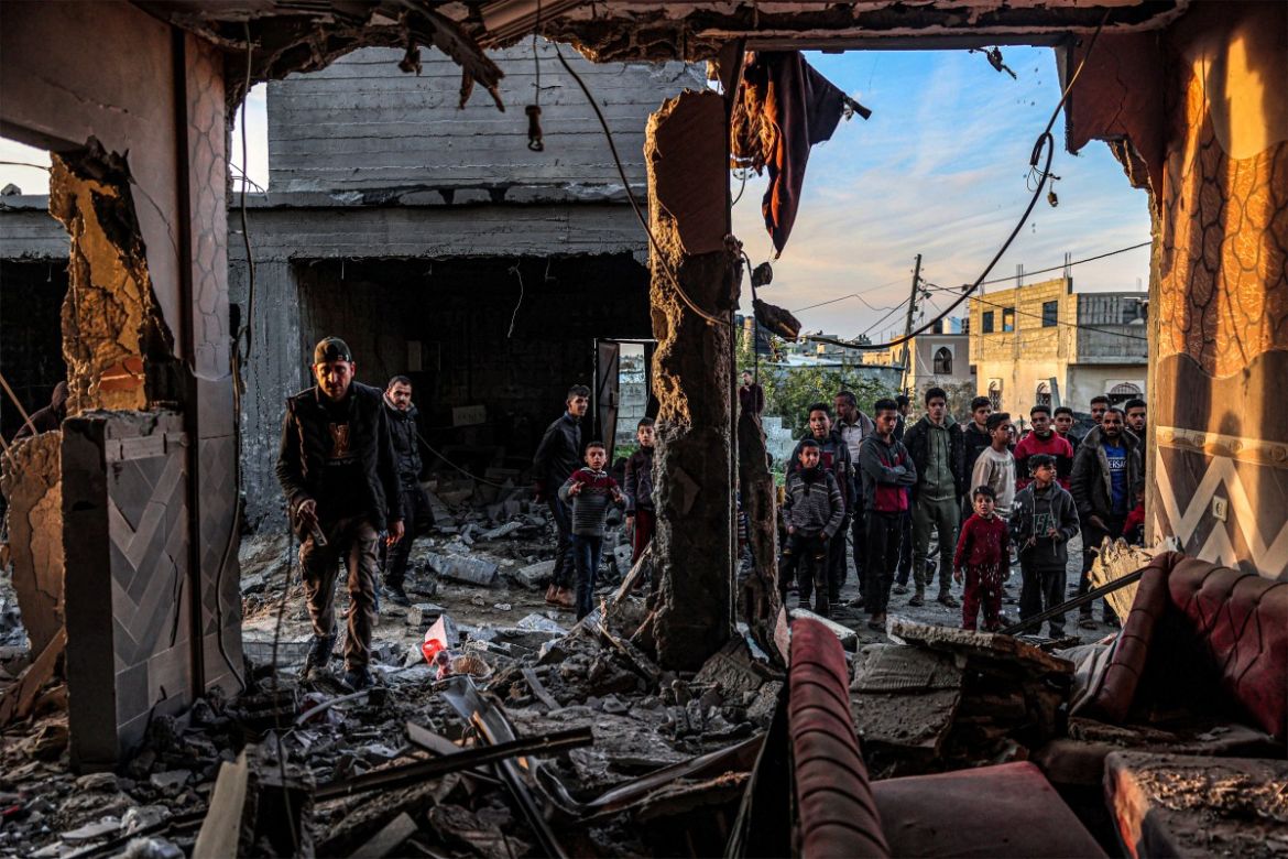 People inspect debris and rubble in a building heavily damaged by Israeli bombardment, in Rafah