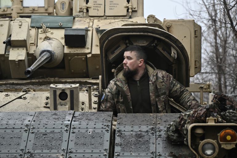 A Ukrainian soldier looking out from the top of a Bradley fighting vehicle