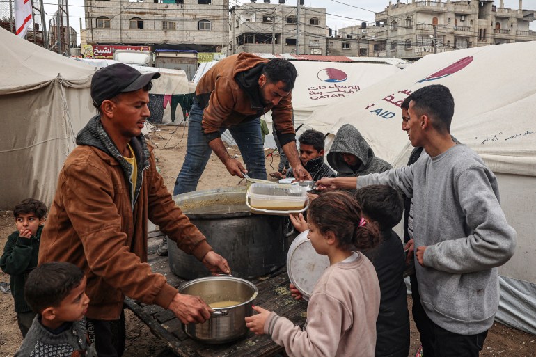 Volunteers distribute portions of red lentil soup to displaced Palestinians in Rafah, southern Gaza Strip, on February 18, 2024.