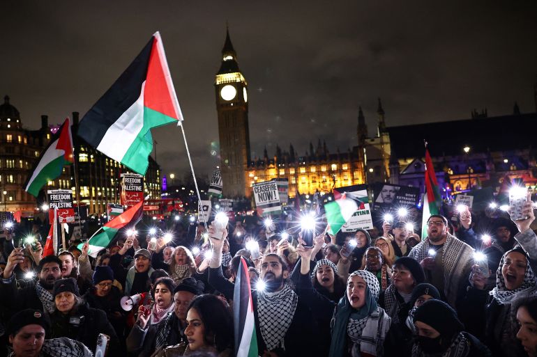 a protest at night time while people wave palestinian flags