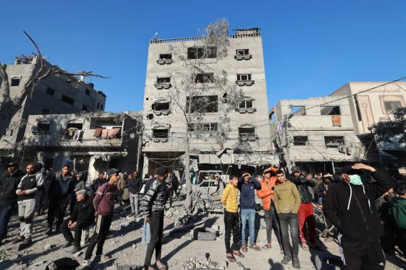Palestinian men stand near damaged buildings