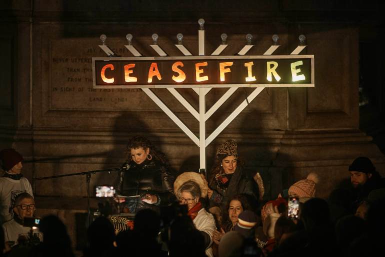 A menorrah with the word "ceasefire" written on it glows in the night.