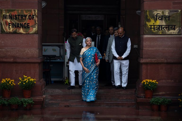 Indian Finance Minister Nirmala Sitharaman, center, in blue saree, leaves her office for President's house before presenting the federal budget in the Parliament in New Delhi, India