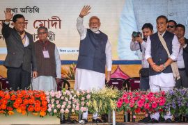 Indian Prime Minister Narendra Modi, center, with his arm raised,, greets the audience as he arrives with Assam Chief Minister Himanta Bishwa Sarma, right, to address a public rally in Guwahati, India, Sunday, Feb. 4, 2024. (AP Photo/Anupam Nath)