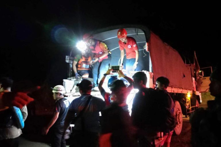 In this photo provided by the Philippine Red Cross, volunteers assists residents evacuate to safer grounds following a landslide at their village at Maco, Davao de Oro province