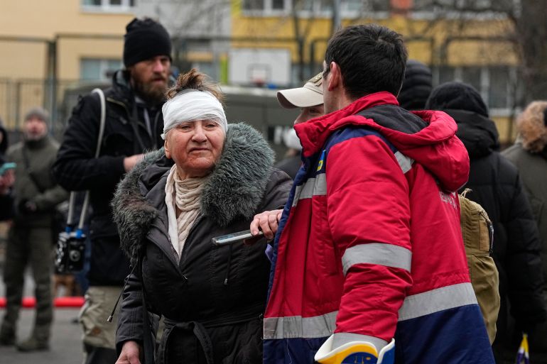 A owman with her head bandaged after the Russian attack on Kyiv. She is being helped by a medic.