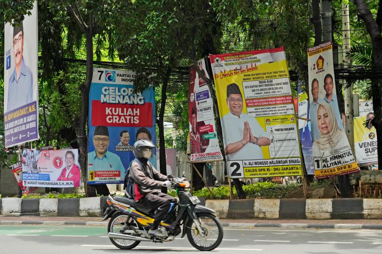 A motorcylist riding past election billboards in Jakarta