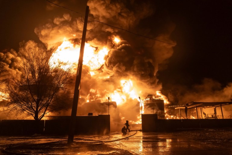 Os bombeiros do posto de gasolina foram atingidos em um ataque russo.  Existem enormes chamas laranja