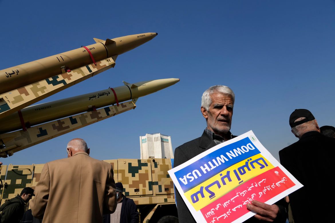 A man carries an anti-U.S. placard upside down in front of the Iranian-made missiles displayed in the annual rally commemorating Iran's 1979 Islamic Revolution in Tehran