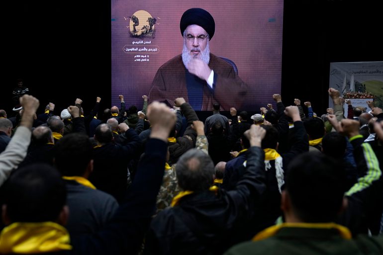 Supporters of the Iranian-backed Hezbollah group raise their fists and cheer, as they listen to a speech by Sayyed Hassan Nasrallah who appears via a video link, during a rally to mark "wounded resistant's day," in the southern suburb of Beirut, Lebanon, Tuesday, Feb. 13, 2024. Nasrallah said his group is committed to a ceasefire in southern Lebanon after a settlement is reached in Gaza, but would continue attacks if Israel resumes. (AP Photo/Hussein Malla)