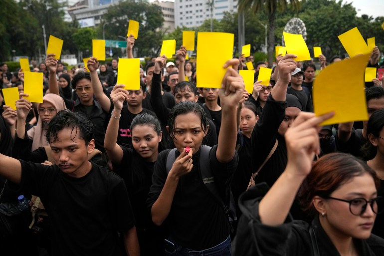 Protesters showing a 'yellow card' for Jokowi after the election. They are all wearing black.