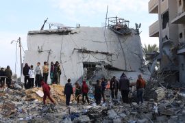 people gather around a destroyed building