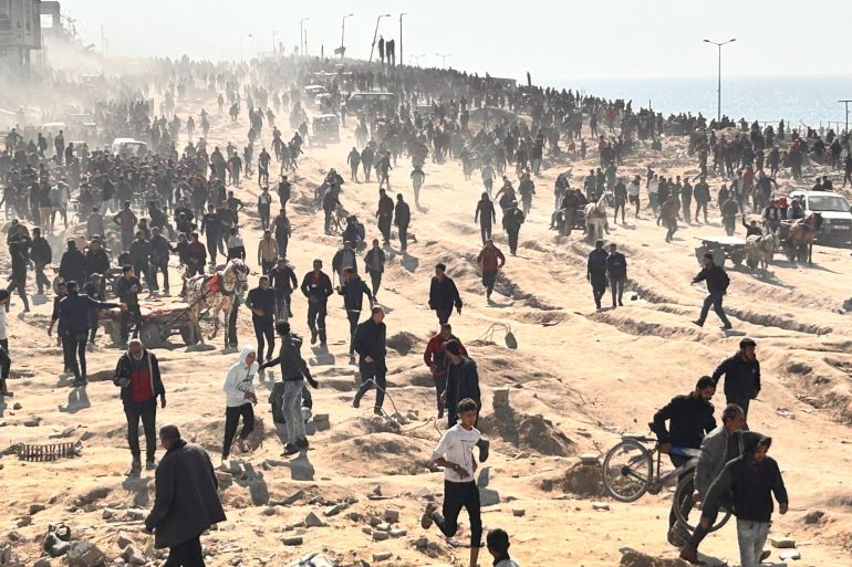 people gather in a sandy area wearing dark coloured clothes