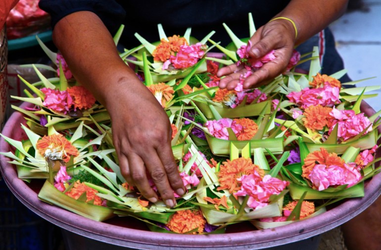 A close up of traditional Balinese offerings. There are small palm leaf baskets containing flowers and petals