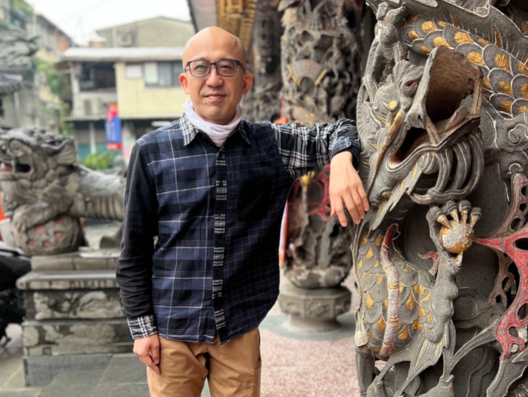 IHua Wu steht neben einer Drachenstatue in einem Tempel in Taipeh, Taiwan. 
