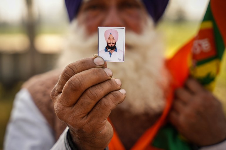 Darshan Singh displying the picture of son who died in the farmer protest two years ago after suffering a heart attack.[Md Meherban/Al Jazeera]