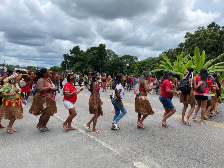 Uma fila de ativistas indígenas marcha em círculo no meio de uma estrada na Bahia, um estado do Brasil.