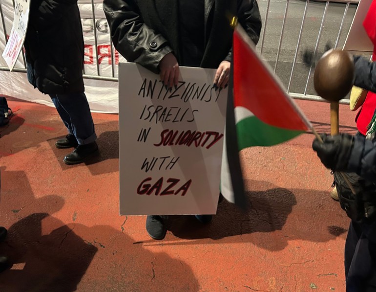 A person — whose face is cropped from the photo — holds a sign that reads "Anti-Zionist Israelis in solidarity with Gaza"