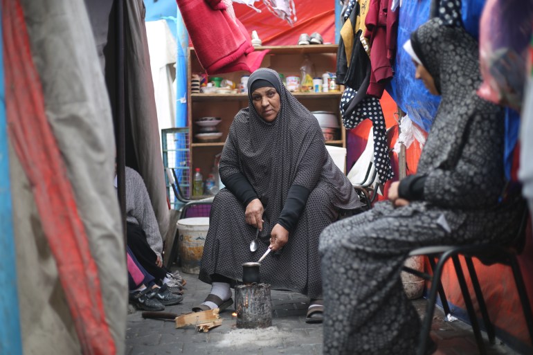 Mona Abdelraheem looks up from the small fire she has made in a can in order to brew some coffee
